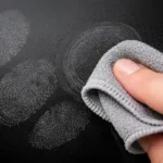 Técnica correcta de limpieza con paño de microfibra para eliminar marcas de dedos en televisores.
